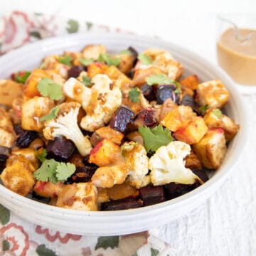 Sheet Pan Tofu and Veggies with Peanut Sauce in a bowl with sauce in the background.