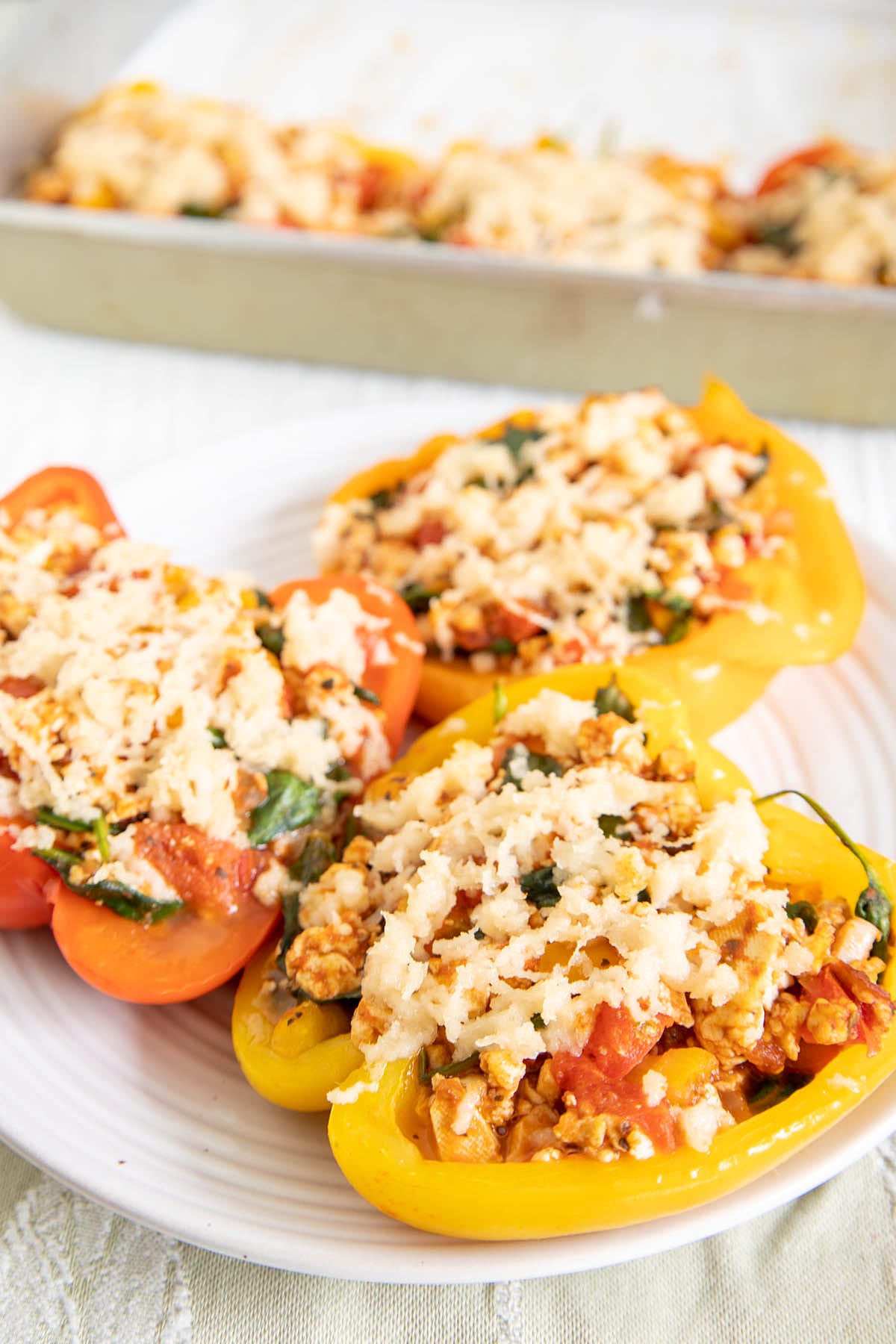 Tofu Stuffed Peppers on a plate with baking dish in the background.