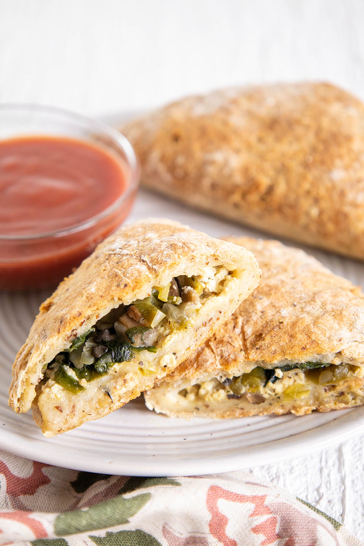 Vegan Calzones on a plate with marinara sauce.
