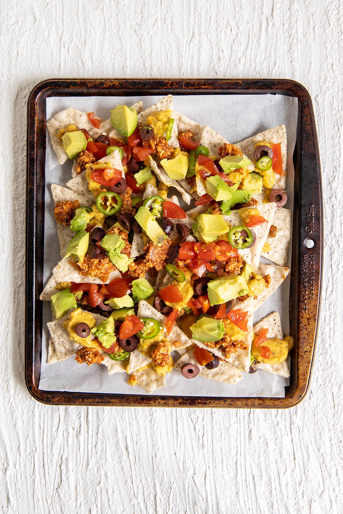 Nachos on a parchment paper lined baking sheet.