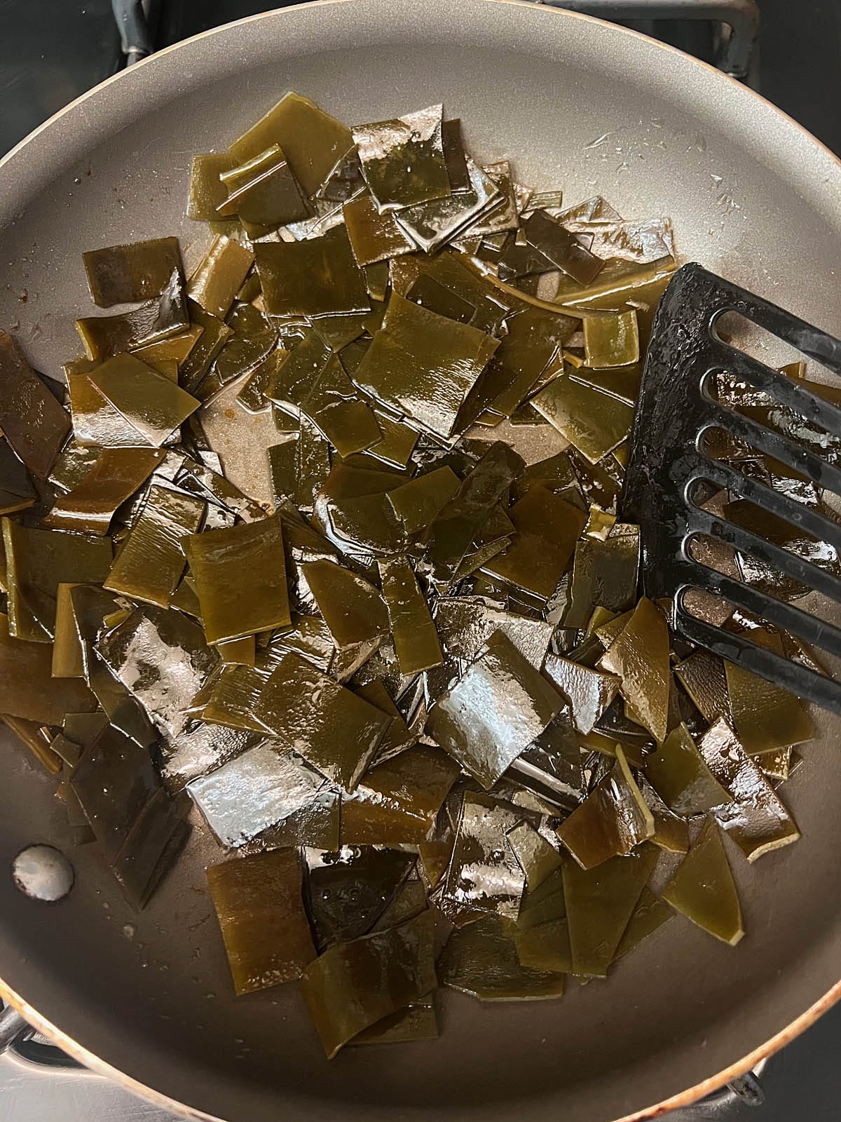 Chopped kelp in a saucepan with sesame oil and tamari.