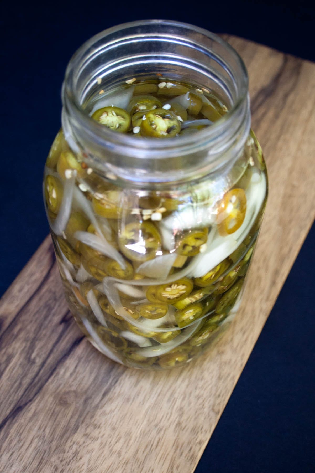 Sugar Free Pickled Peppers and Onions in a glass mason jar on a cutting board.