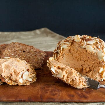 Sun-Dried Tomato and Basil Vegan Cheese Ball on cutting board with crackers.