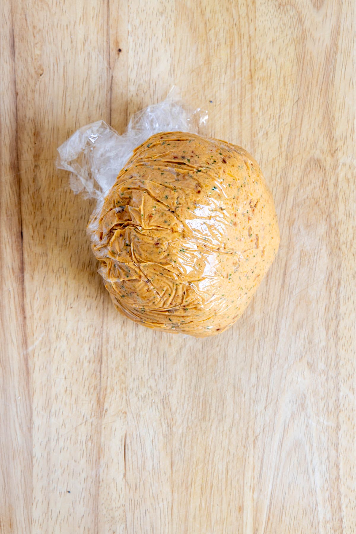 Vegan cheese ball in plastic weapon a cutting board.
