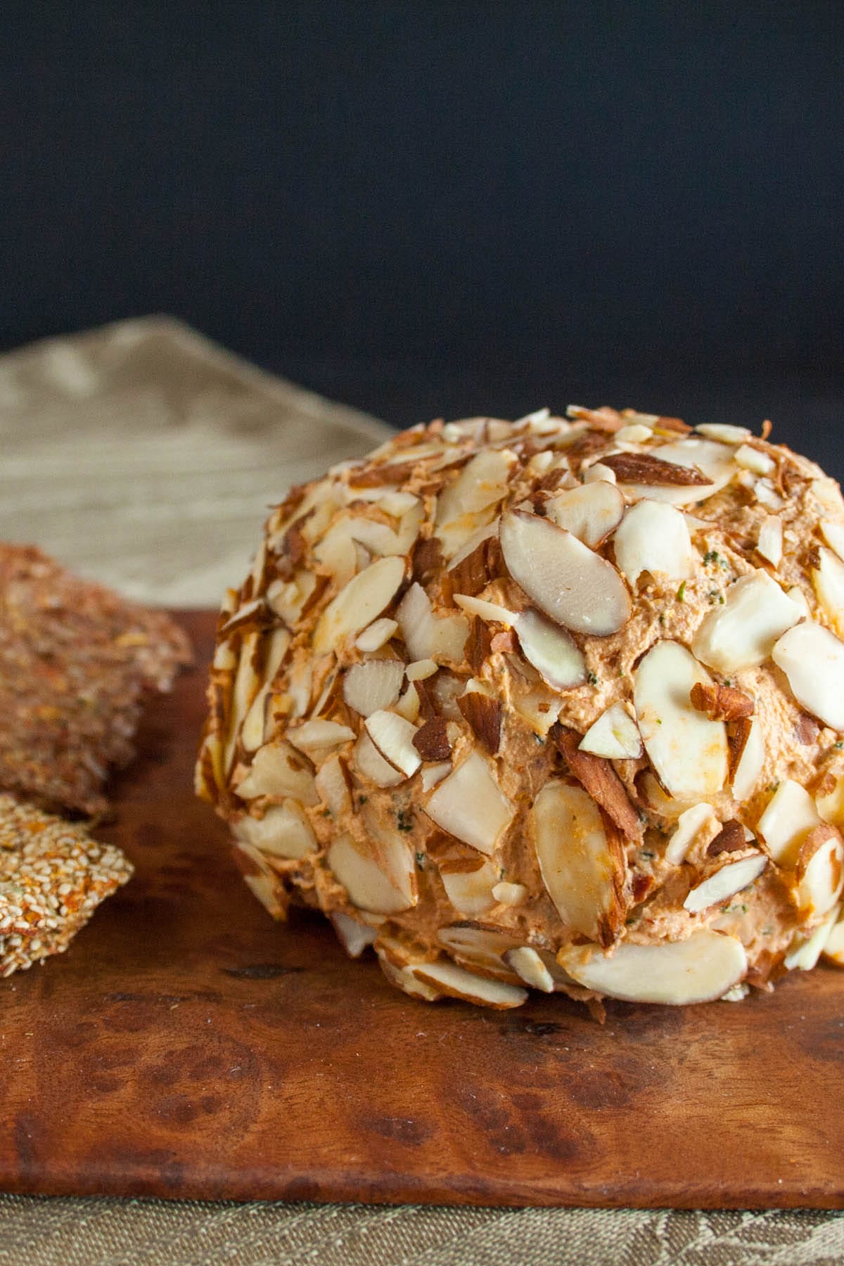 Sun-Dried Tomato and Basil Vegan Cheese Ball on cutting board with  crackers.