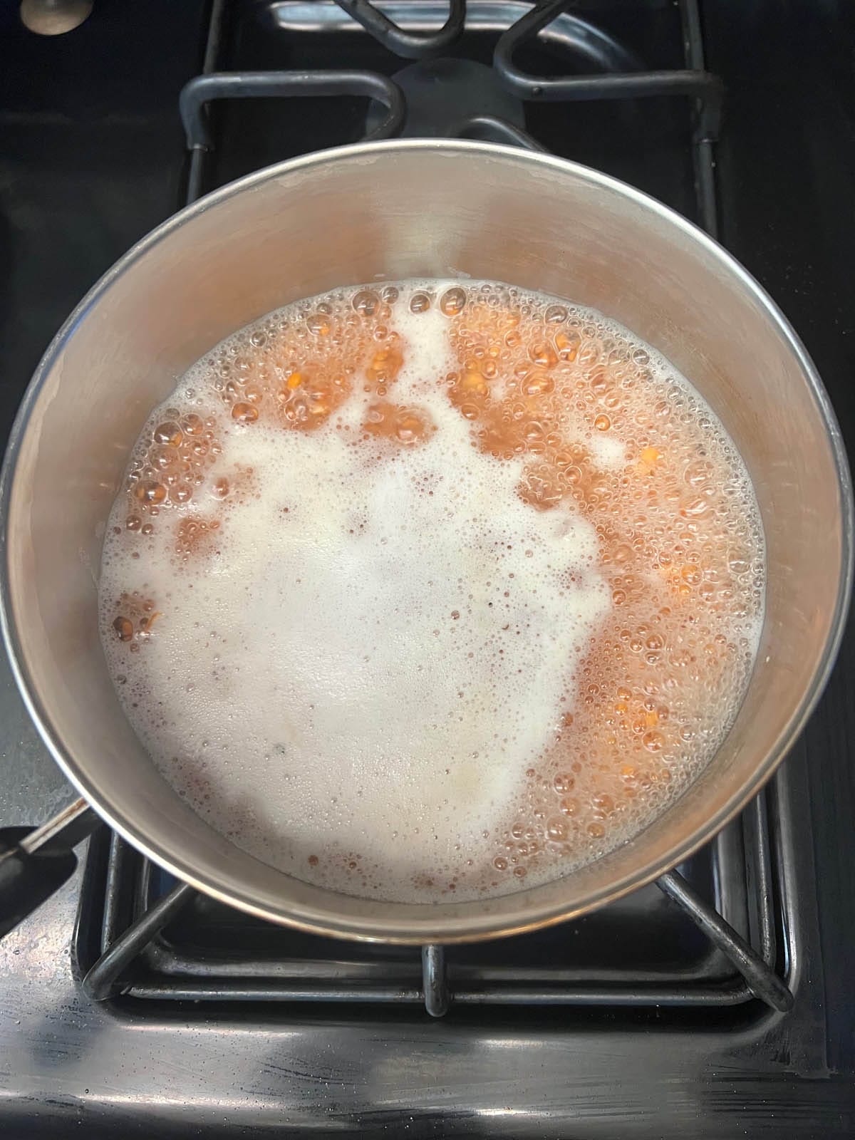 Boiling water and red lentils in a saucepan.