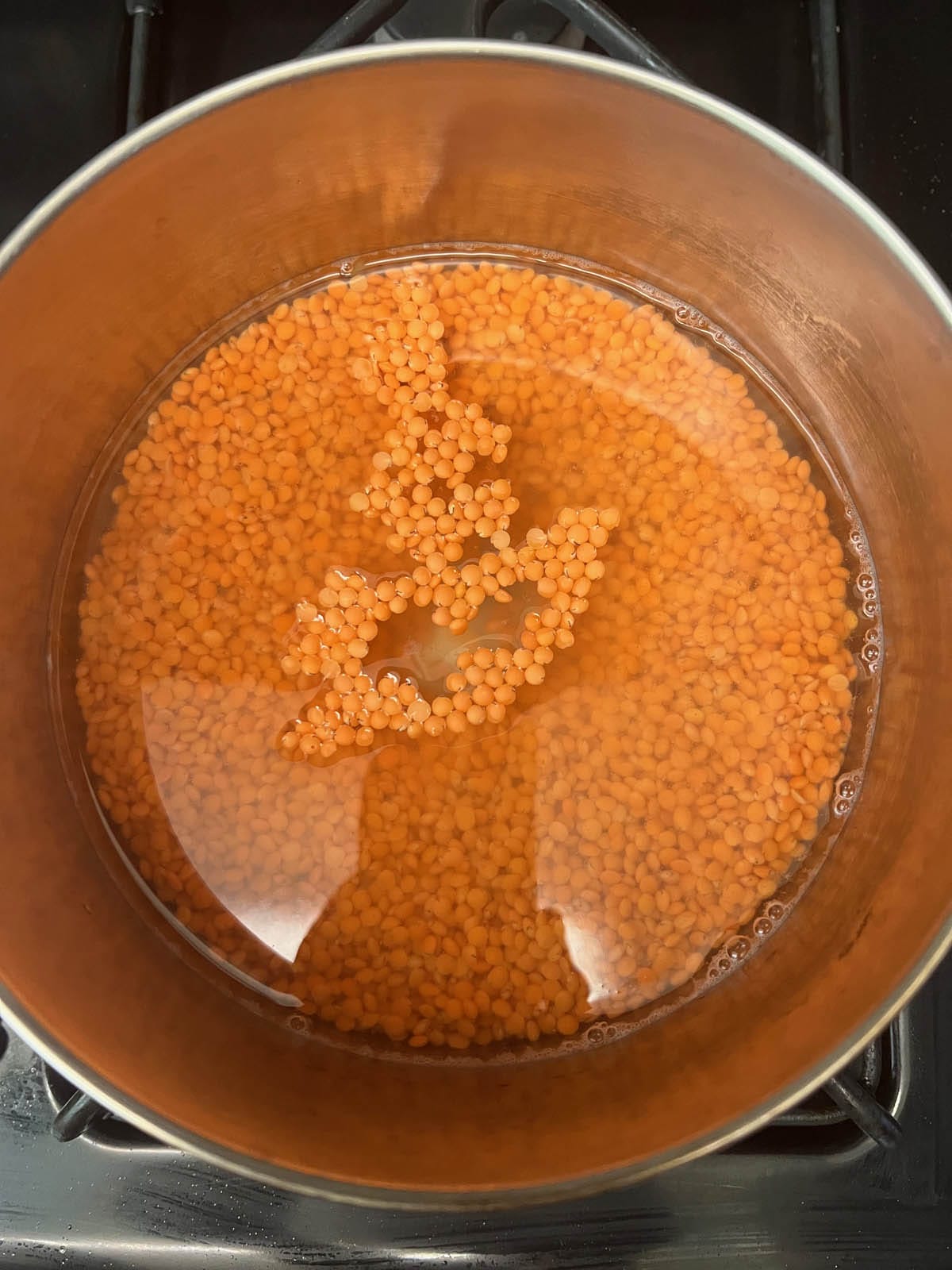Water and red lentils in a saucepan.