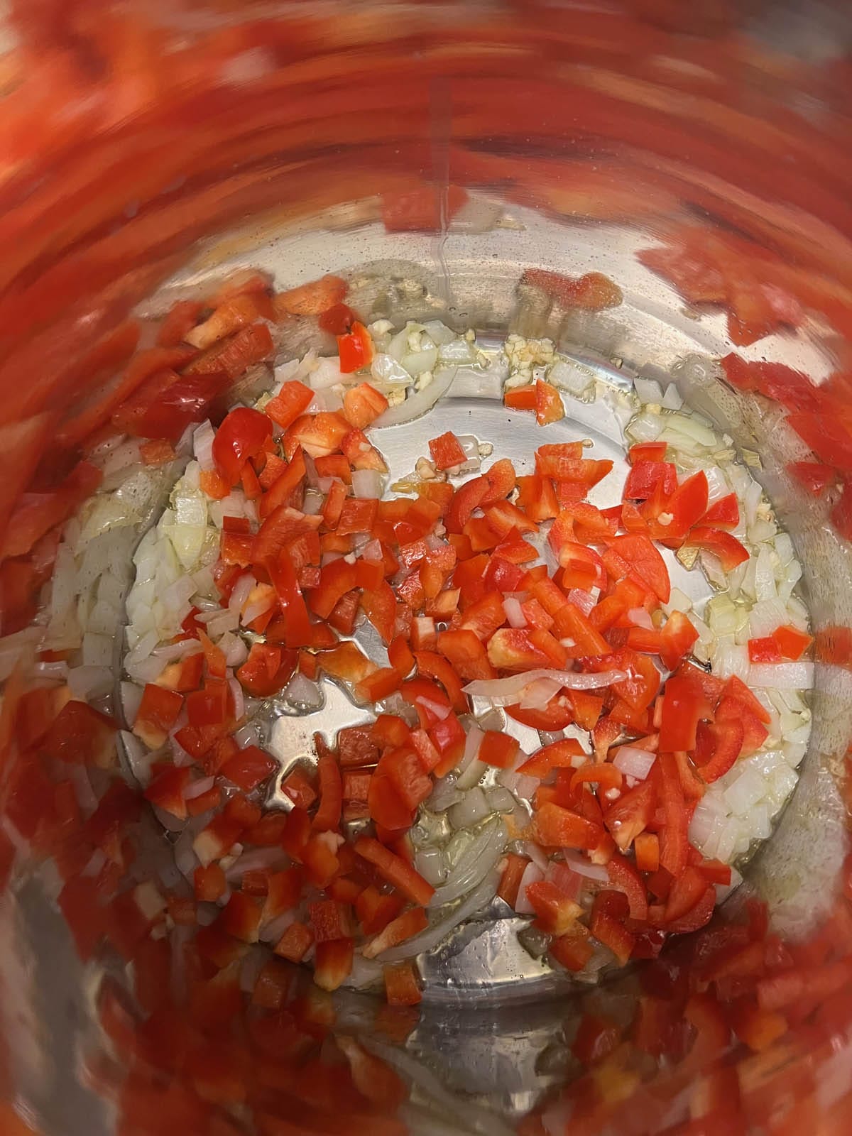 Chopped red bell peppers added to the saucepan.