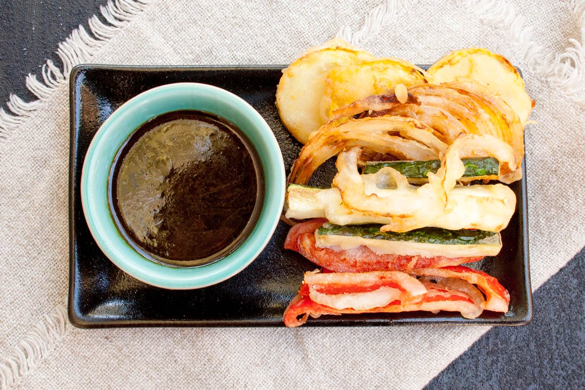 Vegan tempura on a plate with dipping sauce.