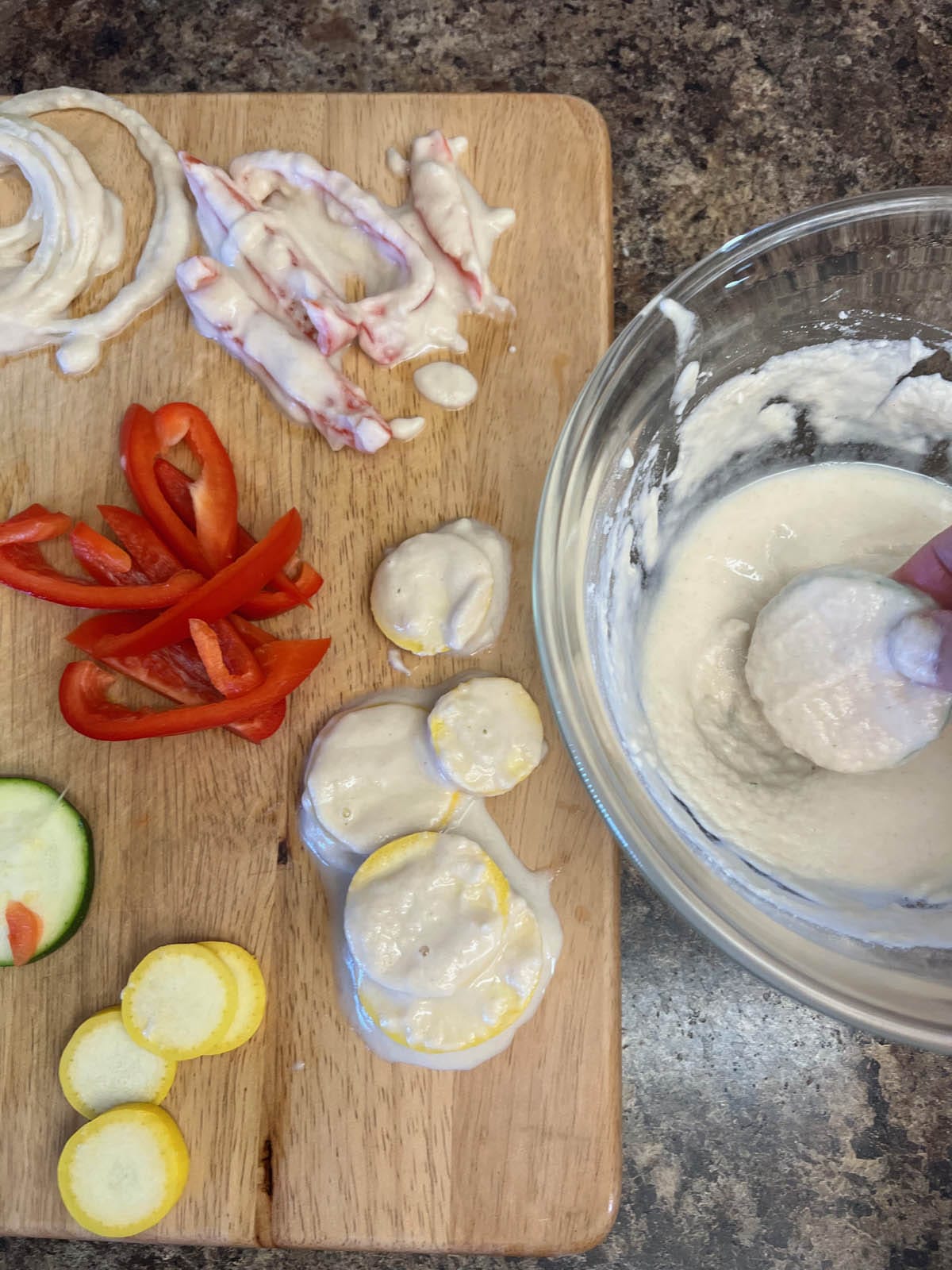 Vegetables being dipped in tempura batter.
