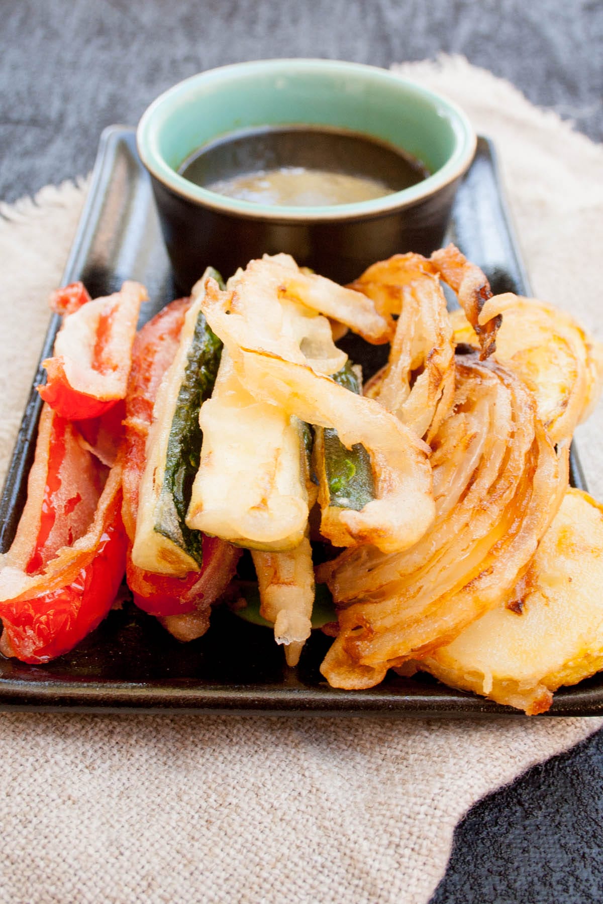 Vegan tempura on a plate with dipping sauce.