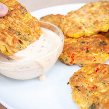 Vegetable fritter bring dipped into vegan chipotle ranch dressing.