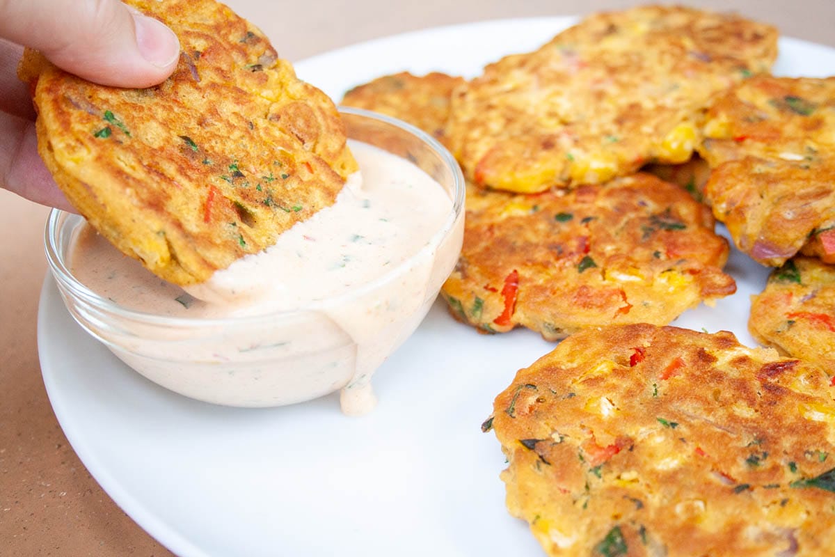 Vegetable fritter bring dipped into vegan chipotle ranch dressing.
