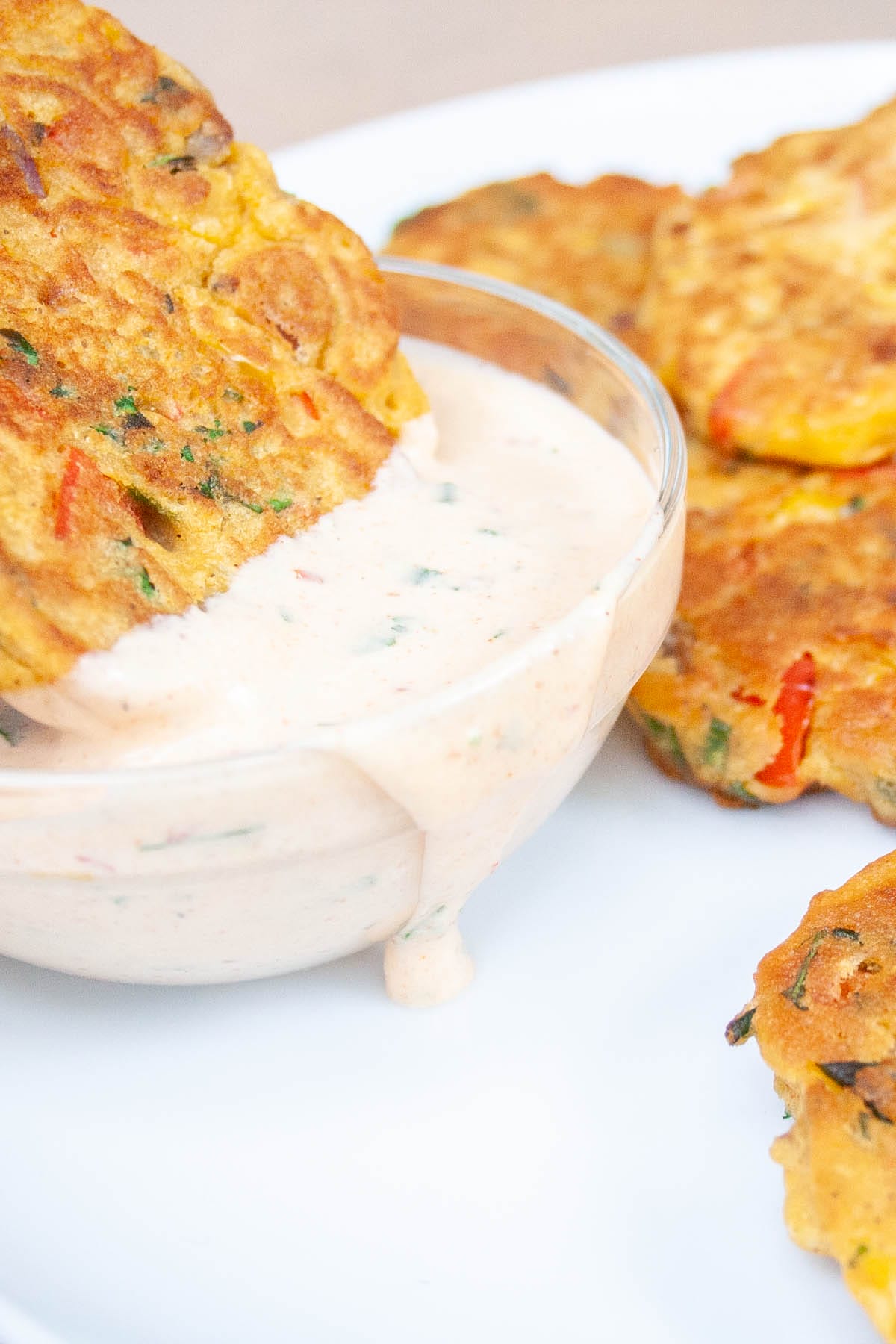 Vegetable fritter bring dipped into vegan chipotle ranch dressing.