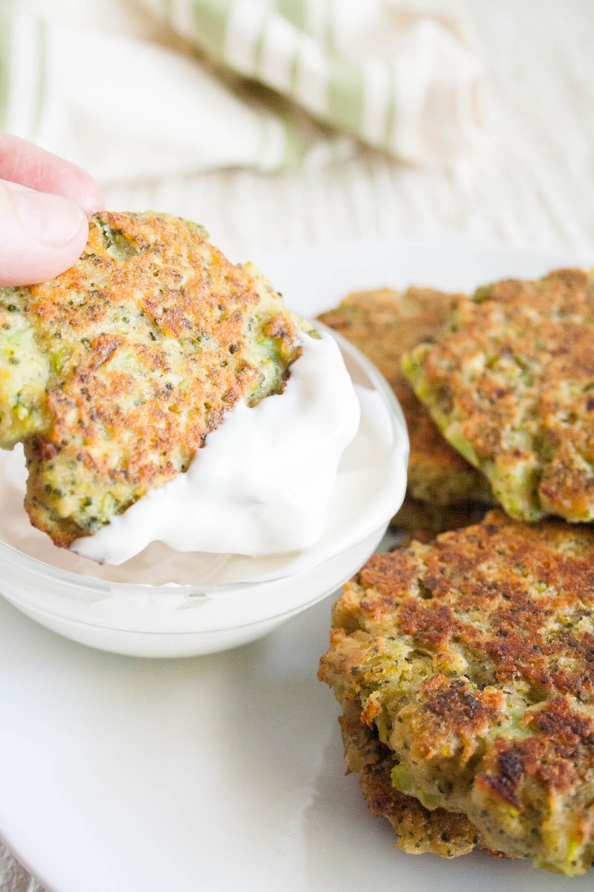 Broccoli Fritter being dipped into dipping sauce.