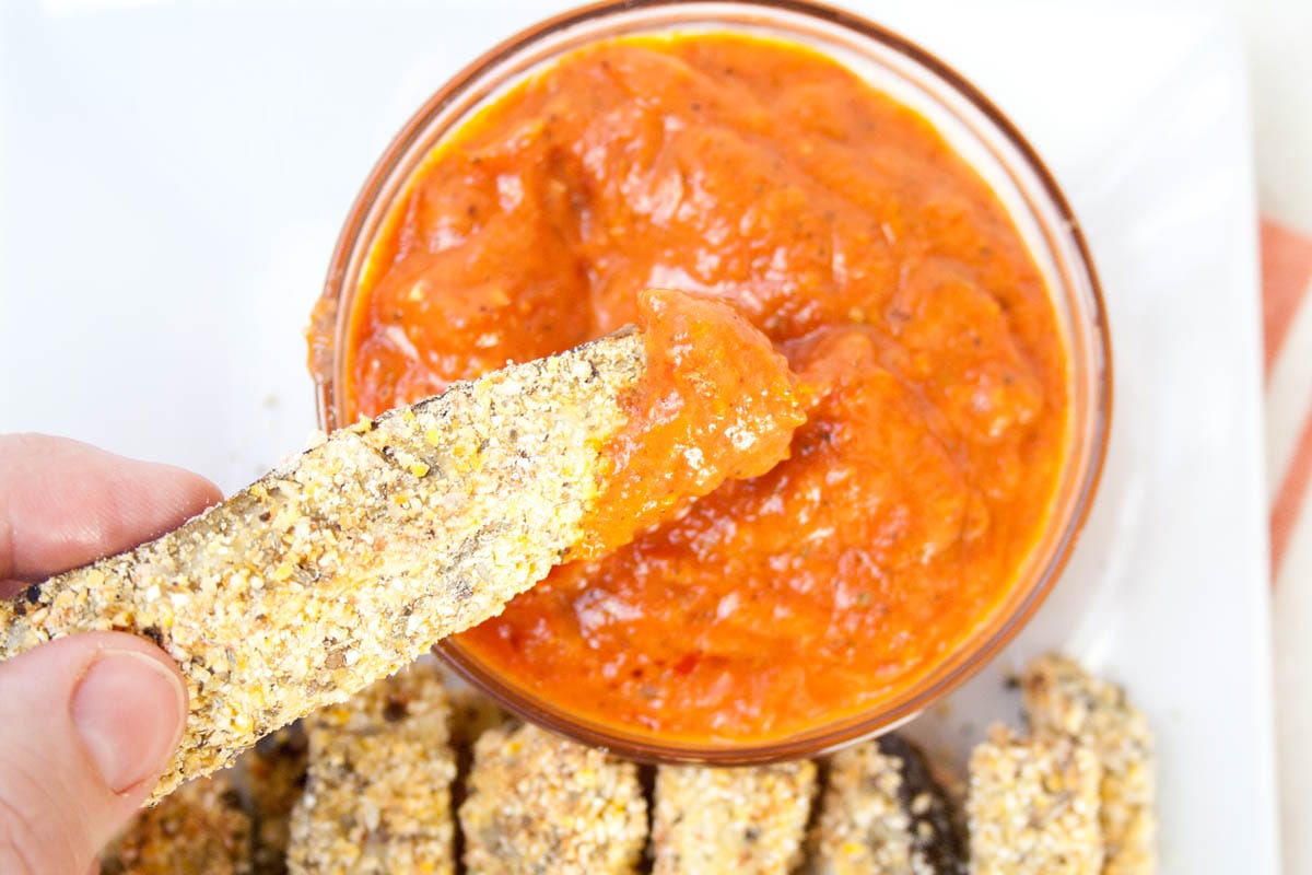 Vegan Eggplant Fry being dipped into sun-dried tomato sauce.