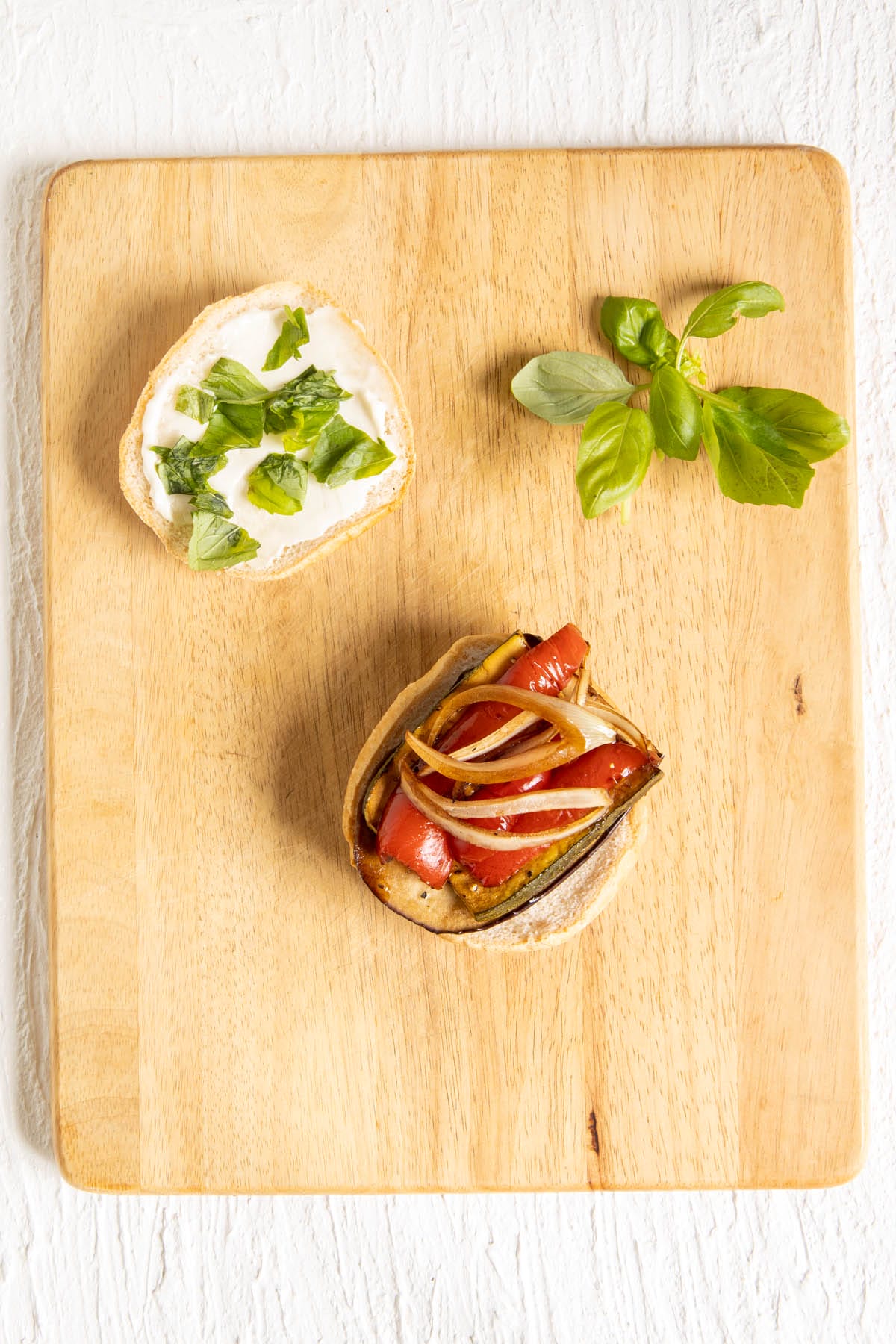 Open faced roasted vegetable sandwich on a cutting board.