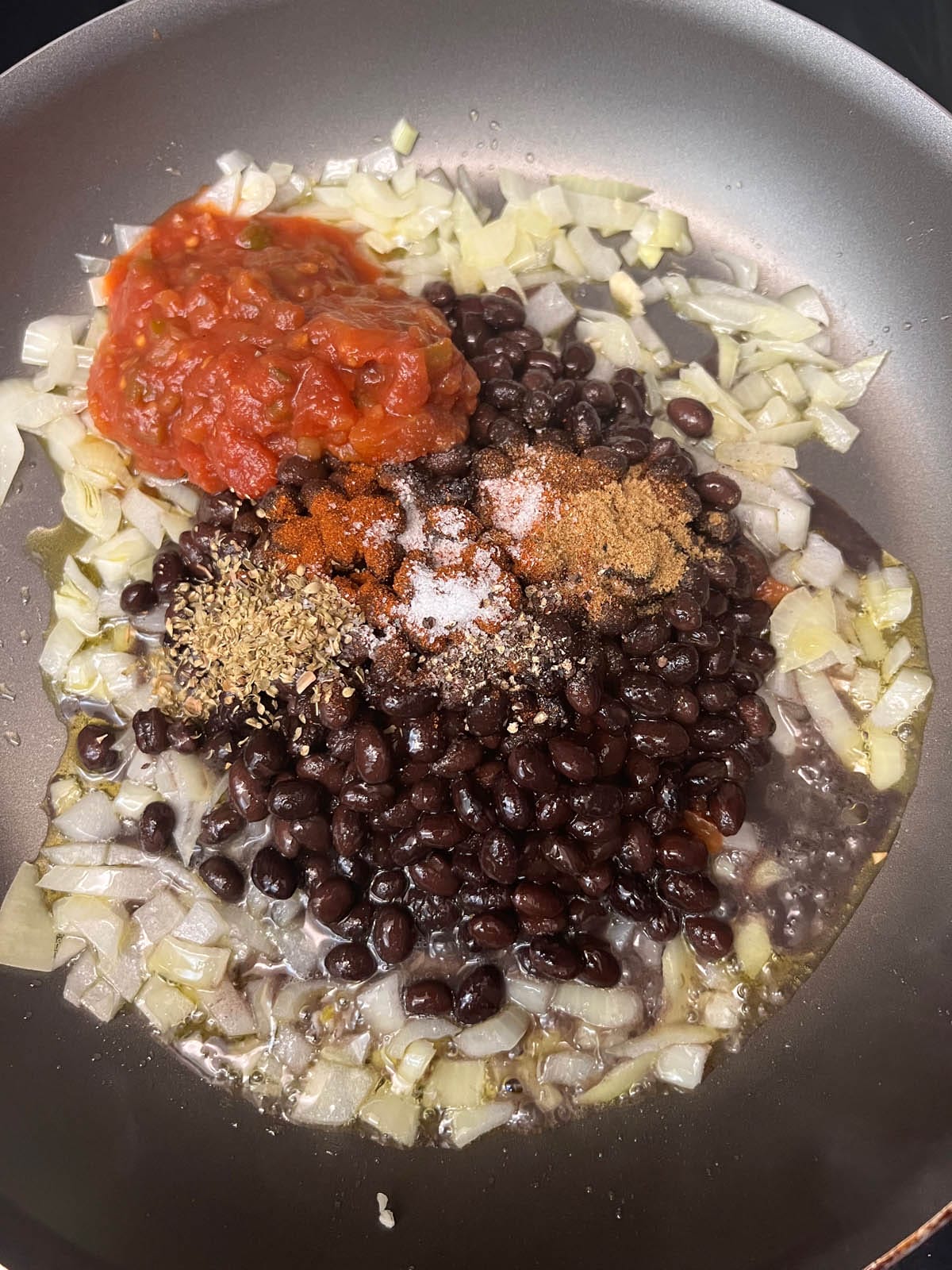 Onions, black beans, salsa, and spices in a skillet.
