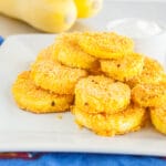 Fried Squash on a plate with yellow squash in the background.