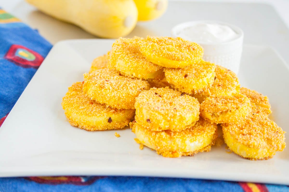 Fried Squash on a plate with yellow squash in the background.