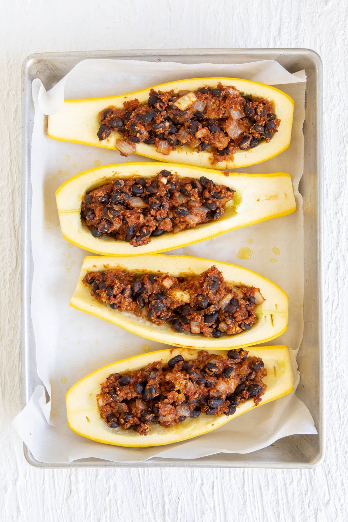 Cooked squash boats in a parchment paper ling baking dish.