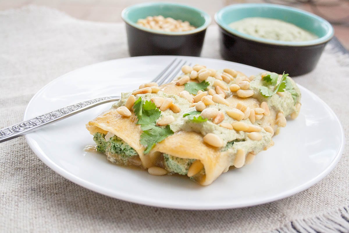 Spinach, Tofu, and Pine Nut Enchiladas (vegan, gluten free) - These vegan enchiladas are rich and satisfying with a creamy roasted green chile sauce. They may just become your new favorite weeknight or weekend meal! Vegan Enchiladas Verdes on a plate with fork.