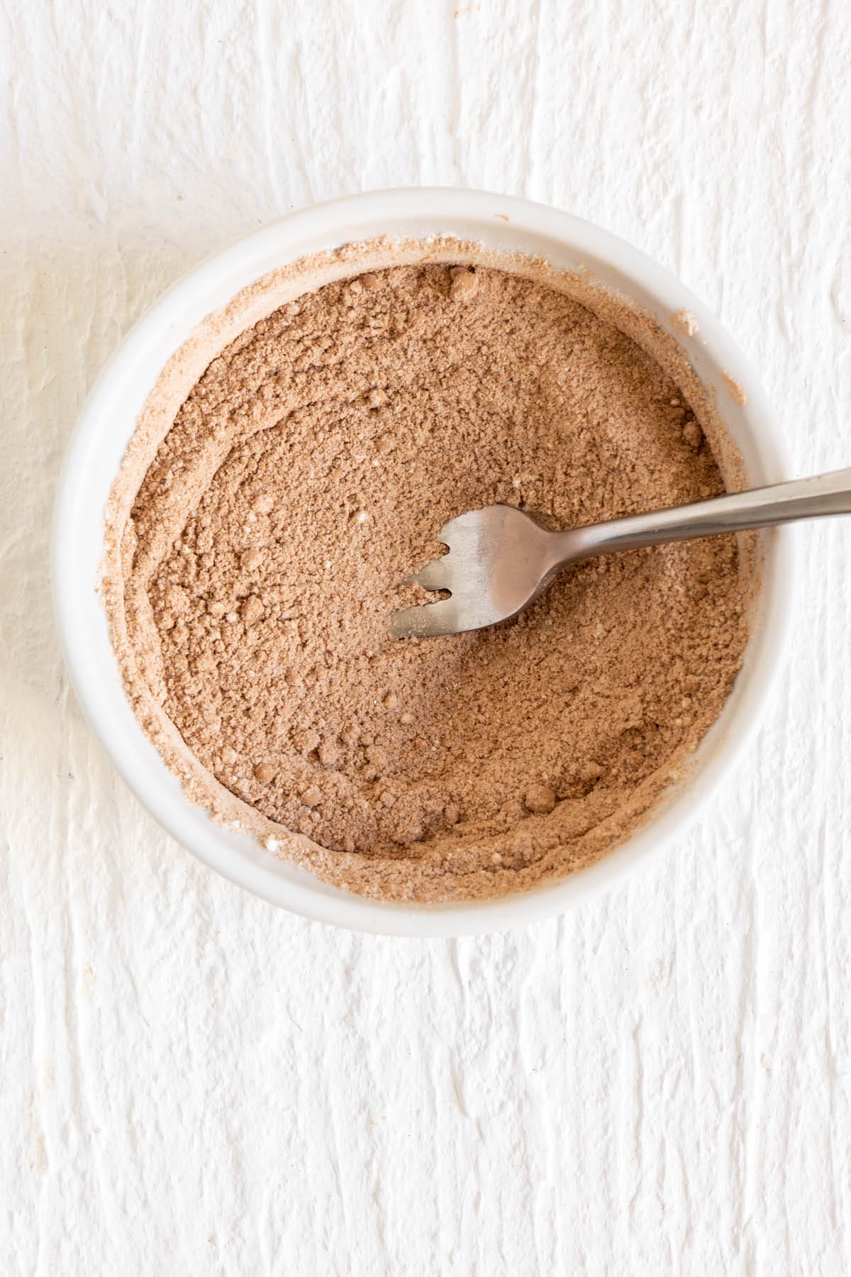 Dry ingredients in a bowl with fork after being whisked.