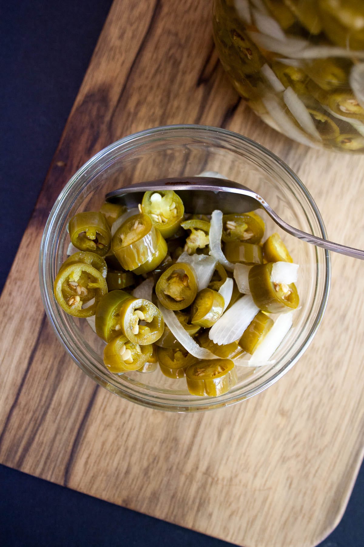 Sugar Free Pickled Peppers and Onions (vegan, gluten free) - These quick pickled peppers are perfect for tacos, sandwiches, or whatever you like! Sugar Free Pickled Peppers and Onions in a small bowl on a cutting board.
