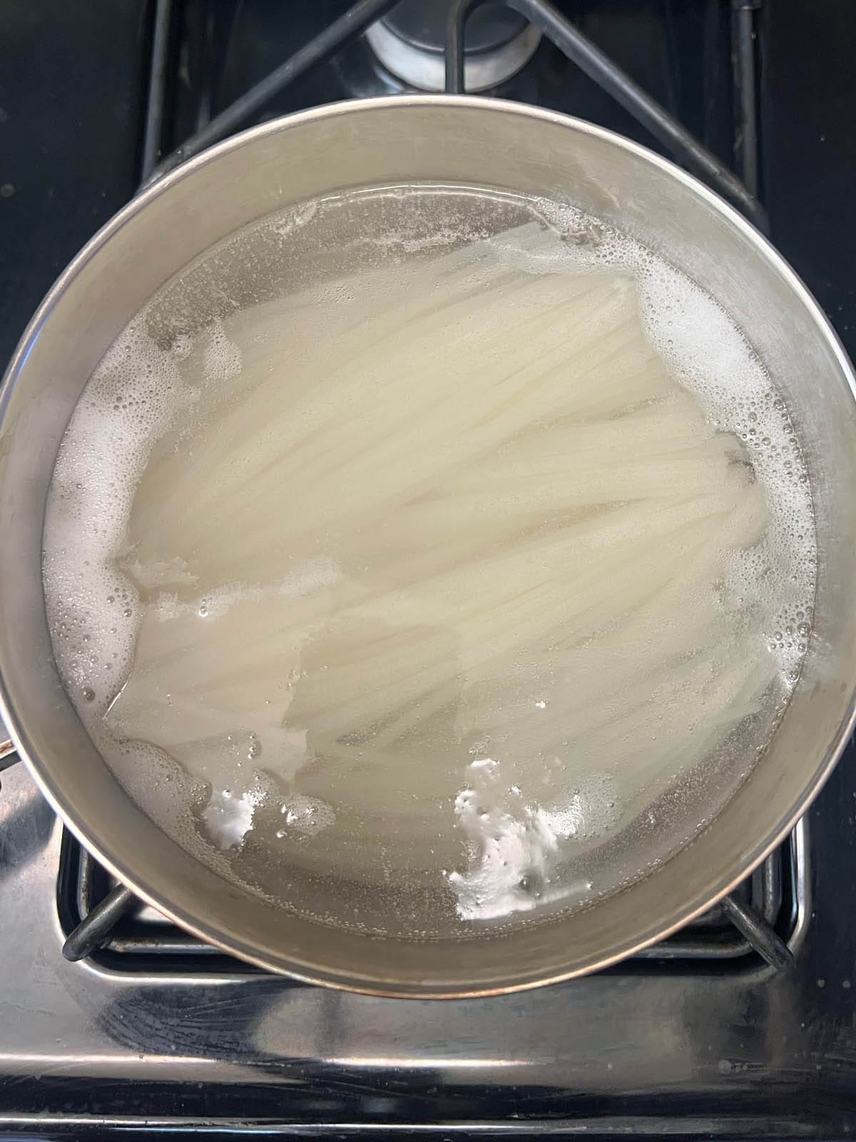 Rice noodles in a pot of boiling water.