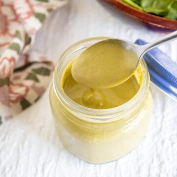 Spicy Cashew Dressing in a jar with spoon.