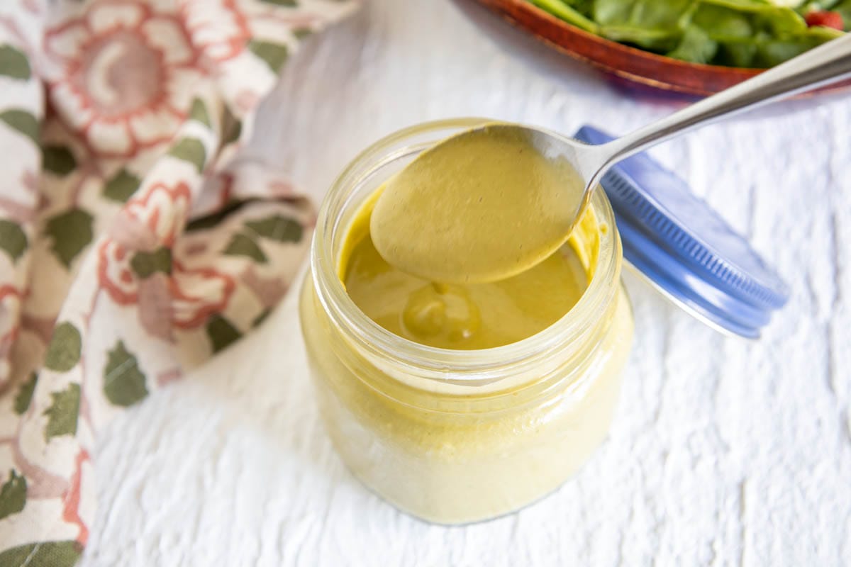 Spicy Cashew Dressing in a jar with spoon.