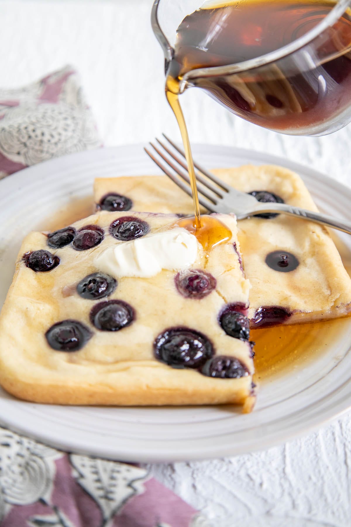 Vegan Sheet Pan Pancakes with maple syrup being poured on them.