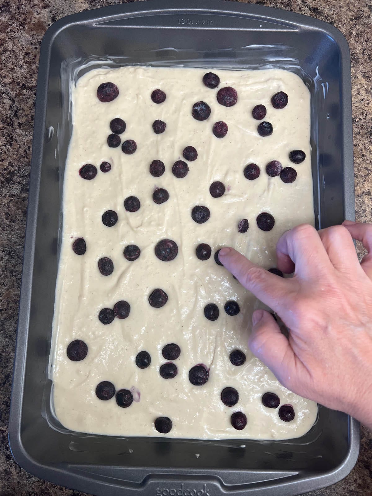 Blueberries being pressed down into the pancake batter.