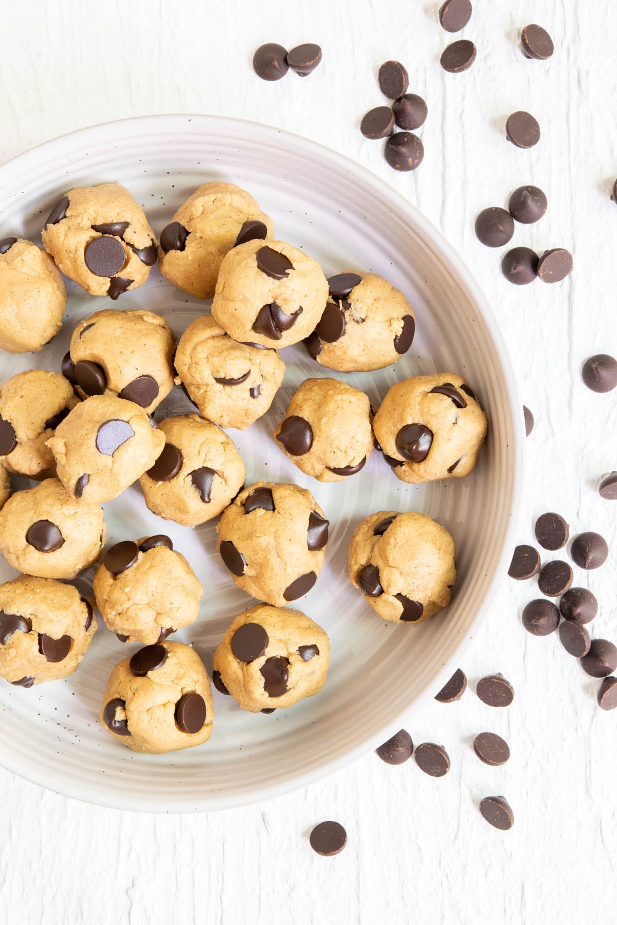 Cookie Dough Protein Bites in a bowl with chocolate chips scattered next to it.