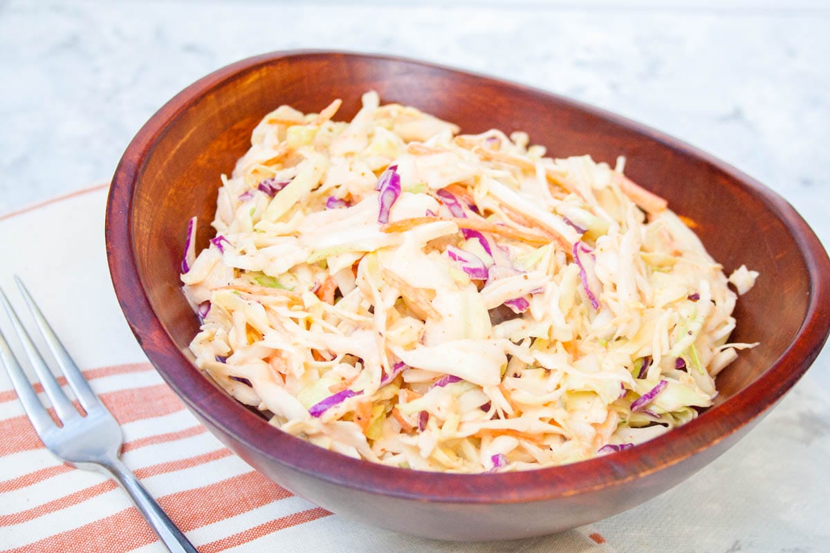 Sriracha Coleslaw in a wood bowl with fork.